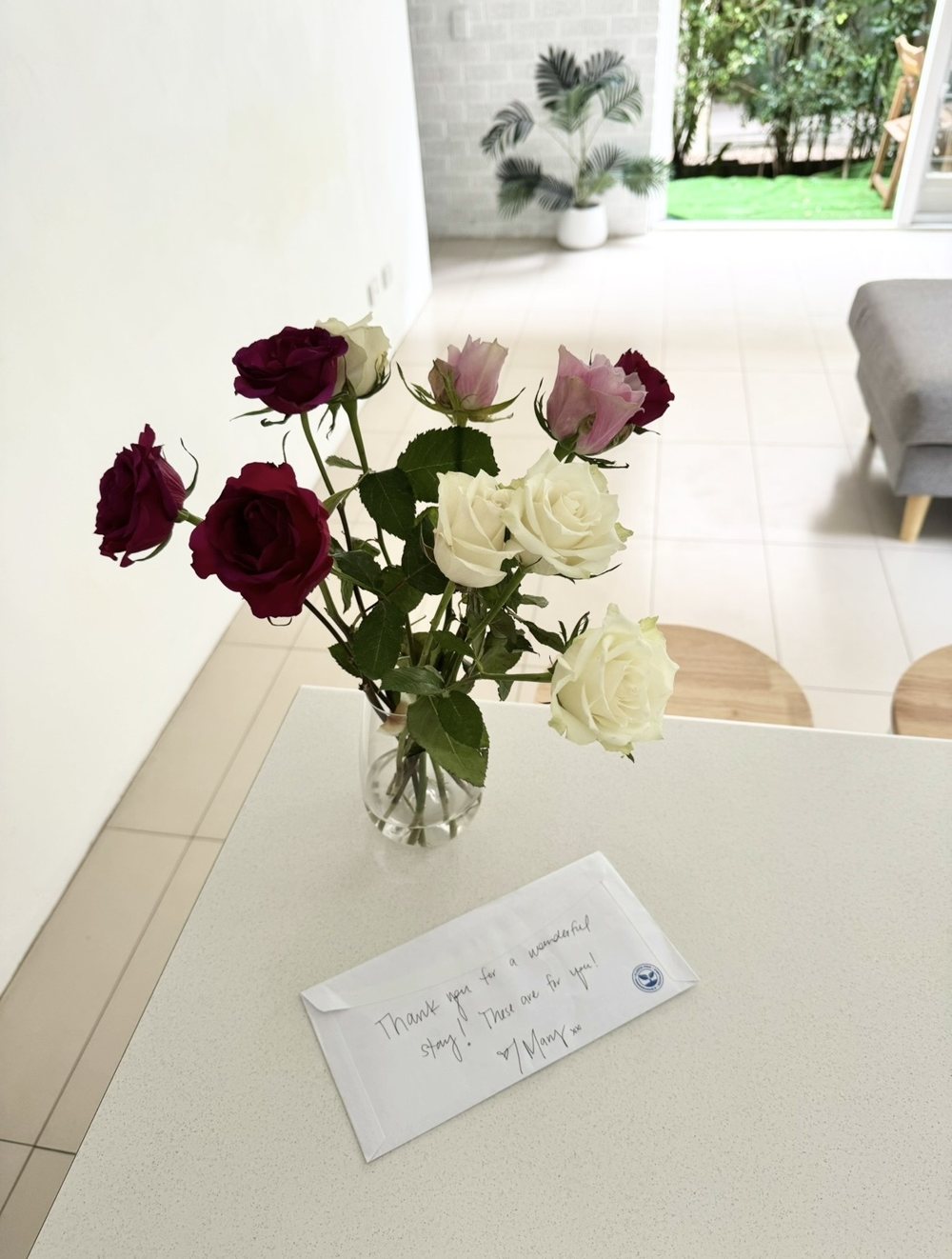 A vase of roses and a handwritten thank-you note left by a guest after their stay